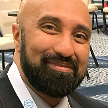 Close-up of Amit Rajput, smiling, with a beard and white lanyard