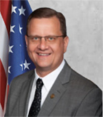 Portrait of Jeff Smith, who is wearing a gray jacket and dark tie, and a white shirt