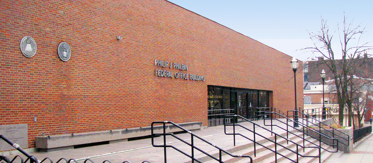 Angle view of the entrance to Philip J Philbin federal office building, a two-story red brick rectangular shape