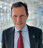 Headshot of Michael Peters. Michael wears a suit with a dark red tie and a GSA lapel pin.