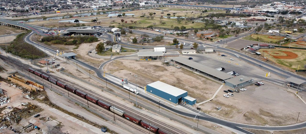 Aerial view of buildings, roads, lots, train tracks and green spaces