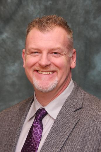 Professional business photo of person wearing gray suit with purple tie.