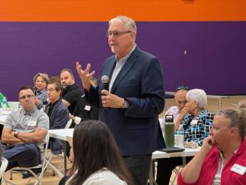 Community members listening to man speaking with microphone