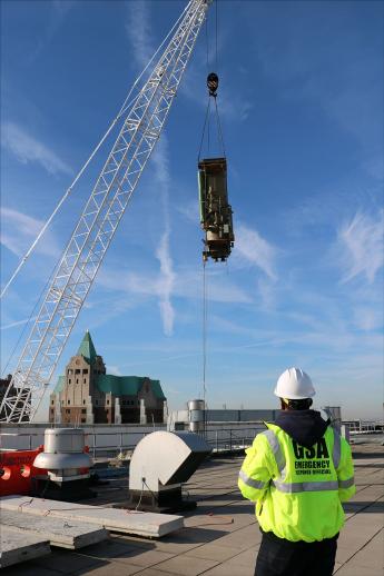 Piece of an old building chiller being moved by a very large crane