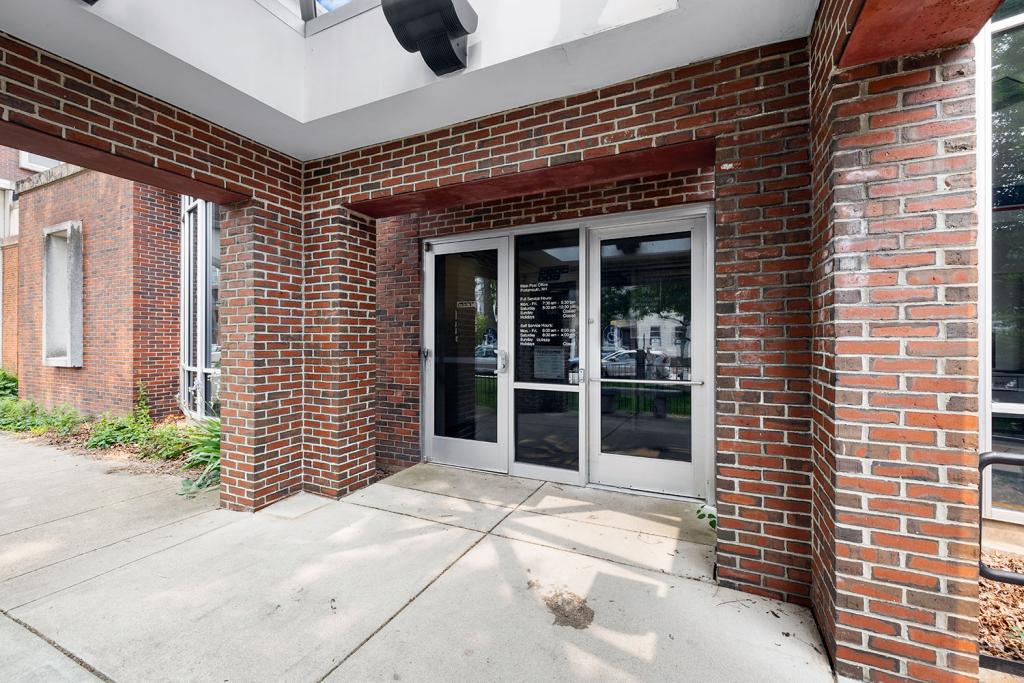 Two glass doors and a window with a red brick entryway covered by a skylight.