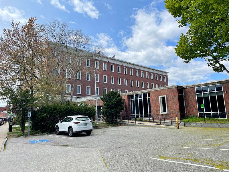 View of an entryway to a red brick building next to a parking area with an accessible ramp.