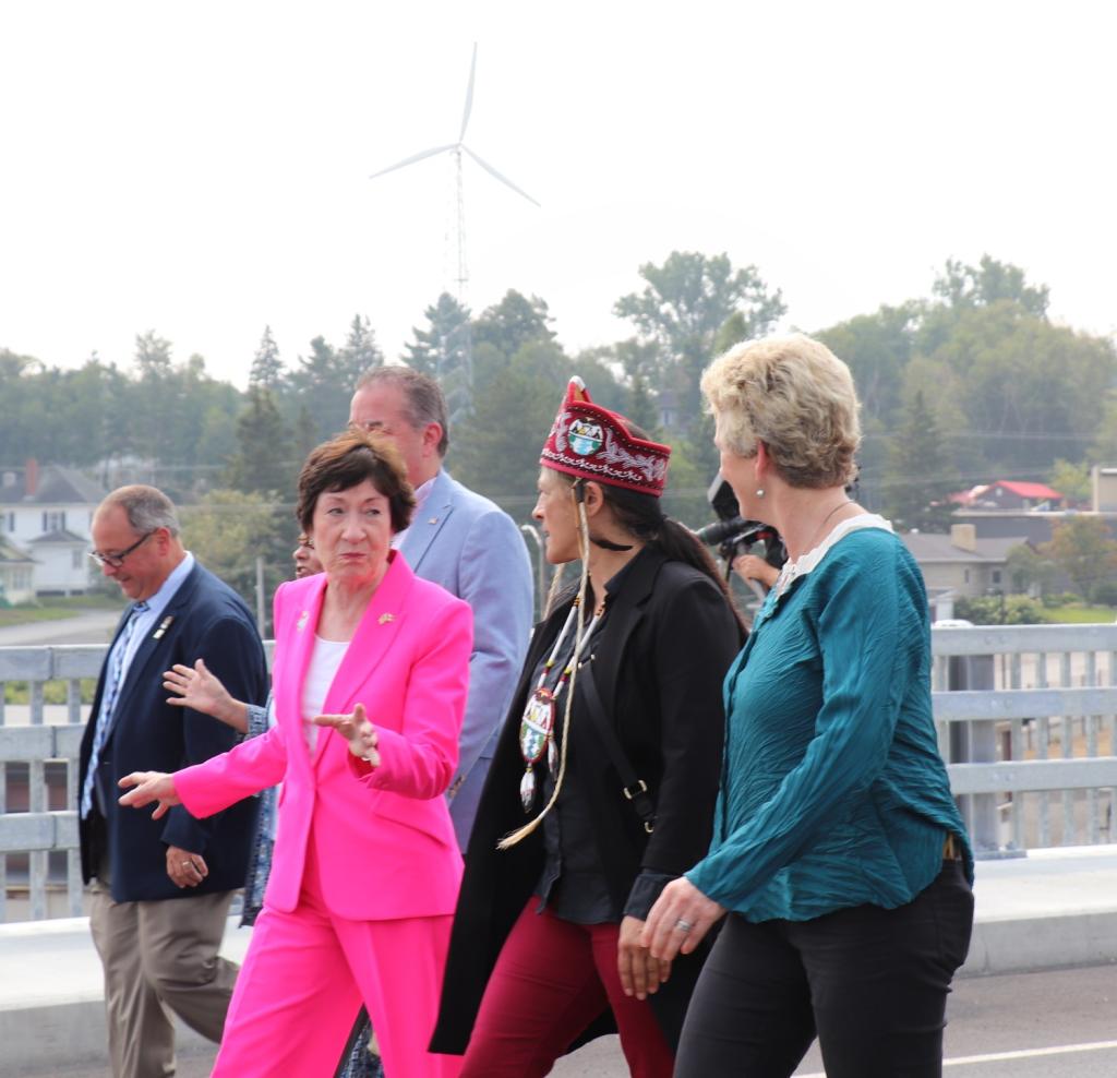 three woman walk side by side down the bridge