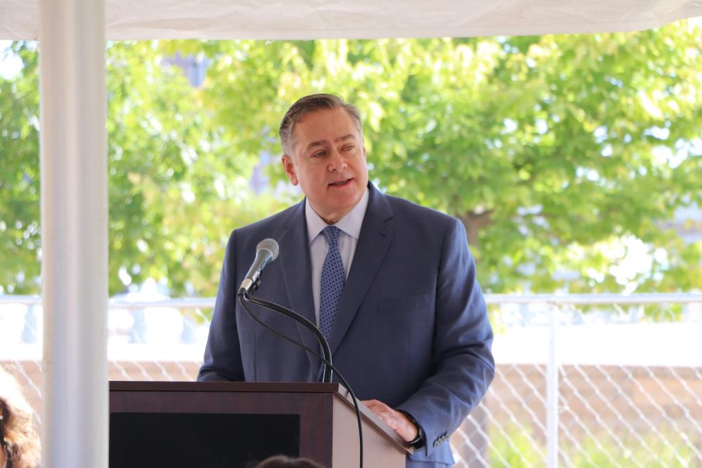 A man speaks into a microphone from behind a lectern