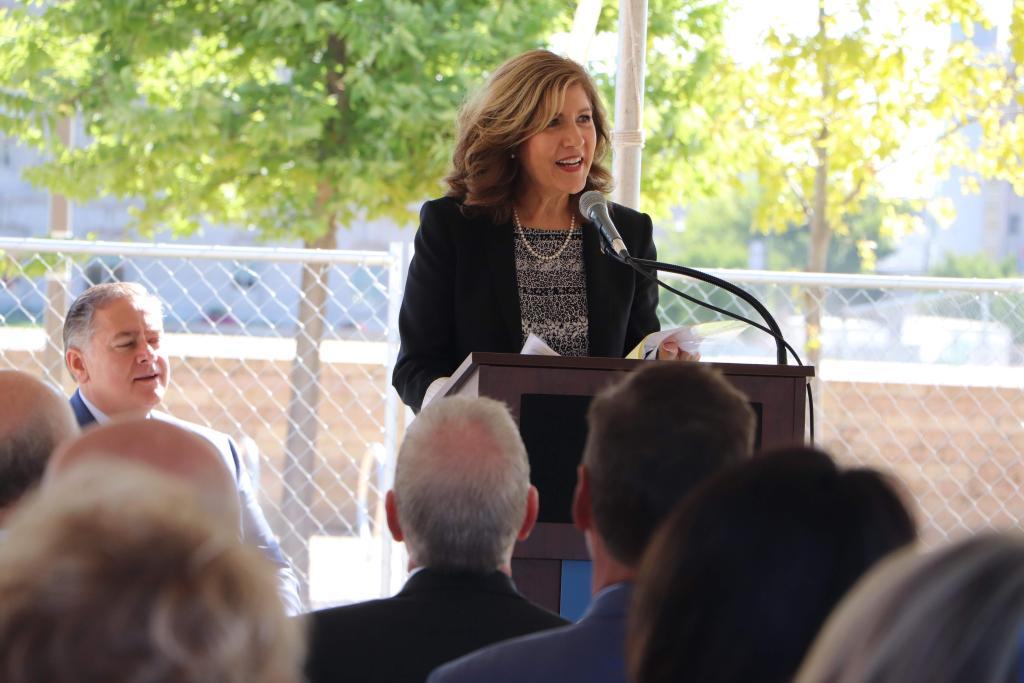 Woman speaks into a microphone from behind a lectern