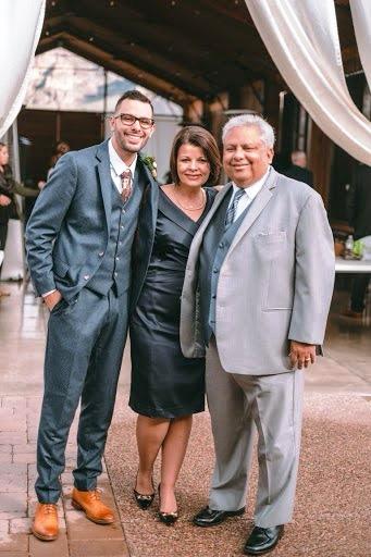 A woman stands between two men all wearing formal dress outdoors.