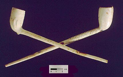 Irish Tenement and Saloon Artifact - Complete examples of two clay pipes; a 19th-century fluted variety, and a "Peter Dorni" style made in Gouda, Holland after 1850.