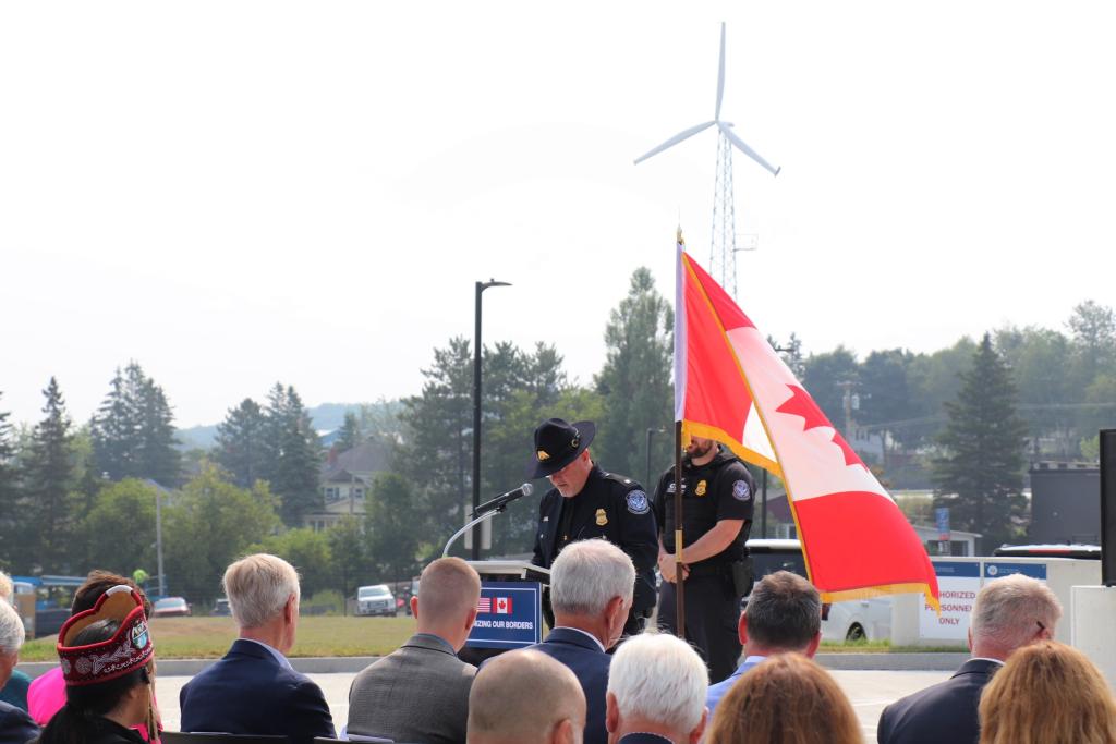 a man stands at the podium in front of a canadian flag