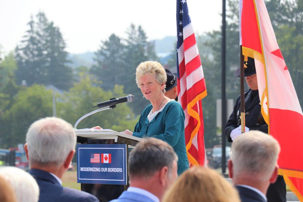 a woman wearing a green shirt stands at the podium