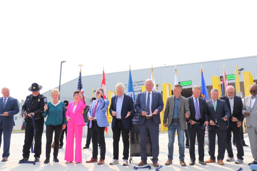 people stand side by side holding ribbon and scissors