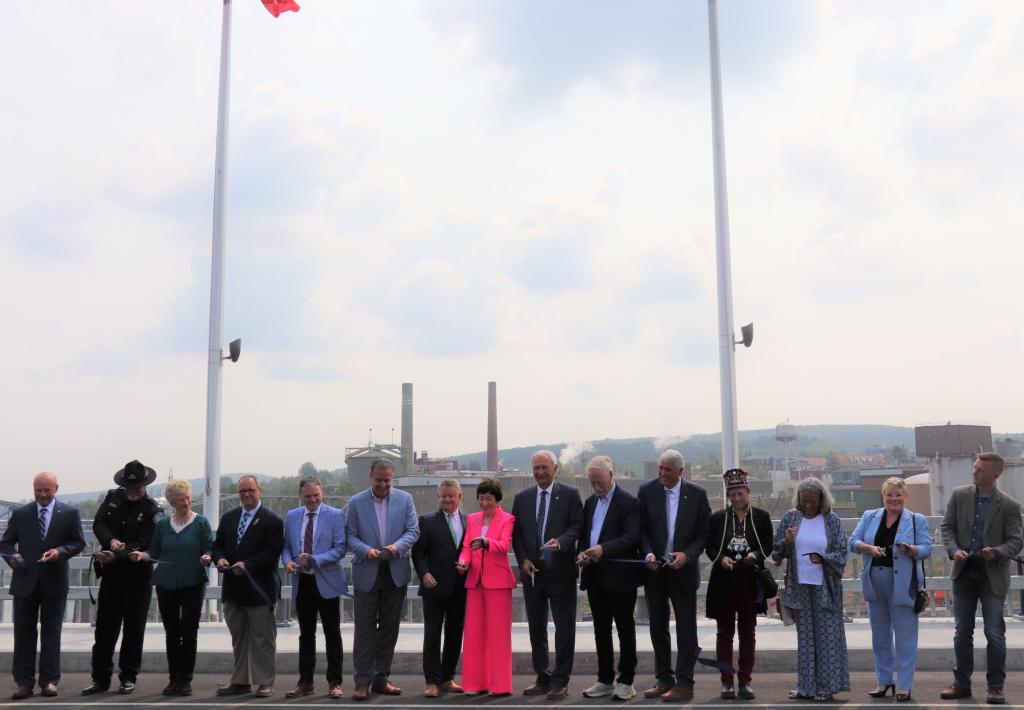 people stand on the bridge holding ribbon and scissors