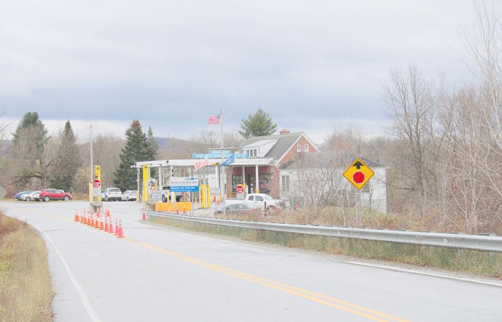 Color photo showing traffic cones leading to the entry with several modern cars parked in front of hte building. 